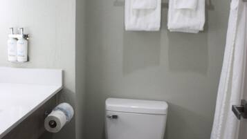 Un baño pequeño con inodoro, toallero con dos toallas, dispensador de papel higiénico y un cesto de basura.
