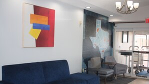 Un sofá azul, dos sillones y un mural con un mapa en un área de recepción.