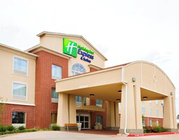 Edificio de Holiday Inn Express & Suites con entrada despejada, zona de espera cubierta y un letrero que indica una altura libre de 4,47 metros.