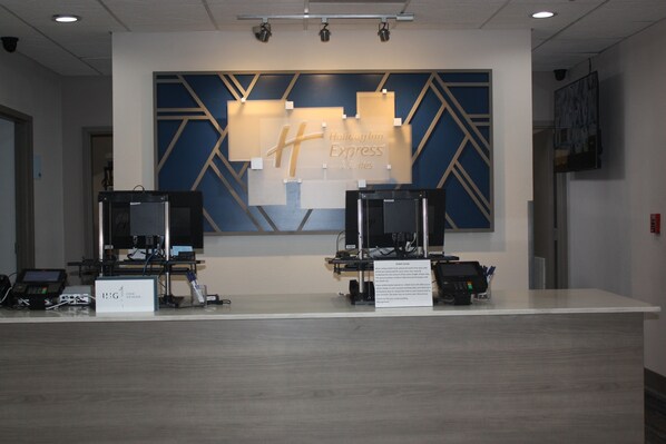 A Holiday Inn Express reception desk with two computer stations, a large blue and gold wall design, and a sign indicating the location. - Holiday Inn Express Hotel & Suites Shamrock North by IHG (Shamrock)