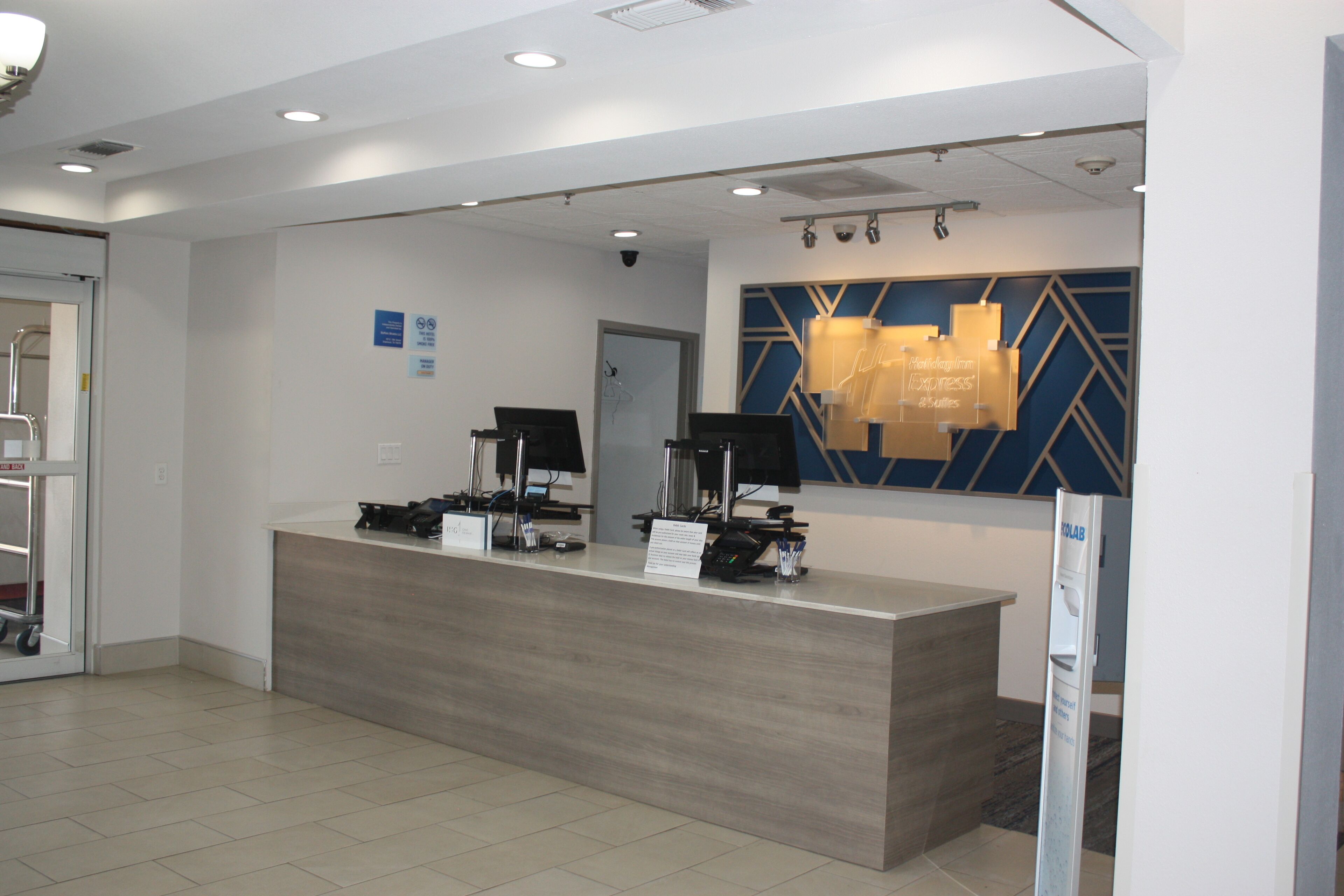 A reception desk with a modern design, a digital screen, and a sign indicating a business lounge.