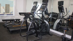 Un gimnasio con cintas de correr, elípticas y un espejo grande.