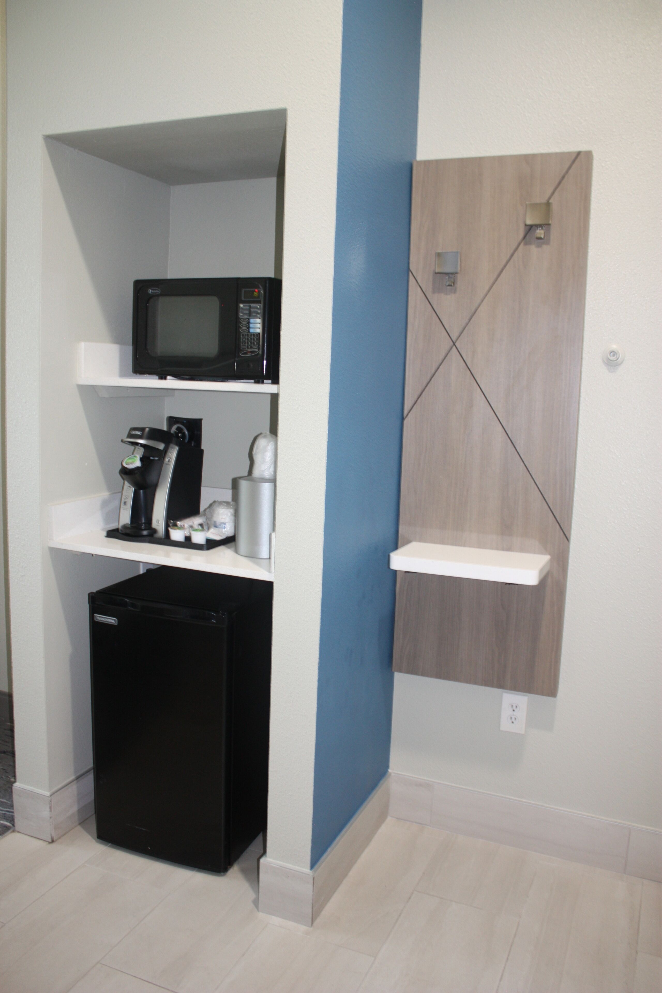 A compact kitchenette with a microwave, coffee maker, and a small refrigerator.