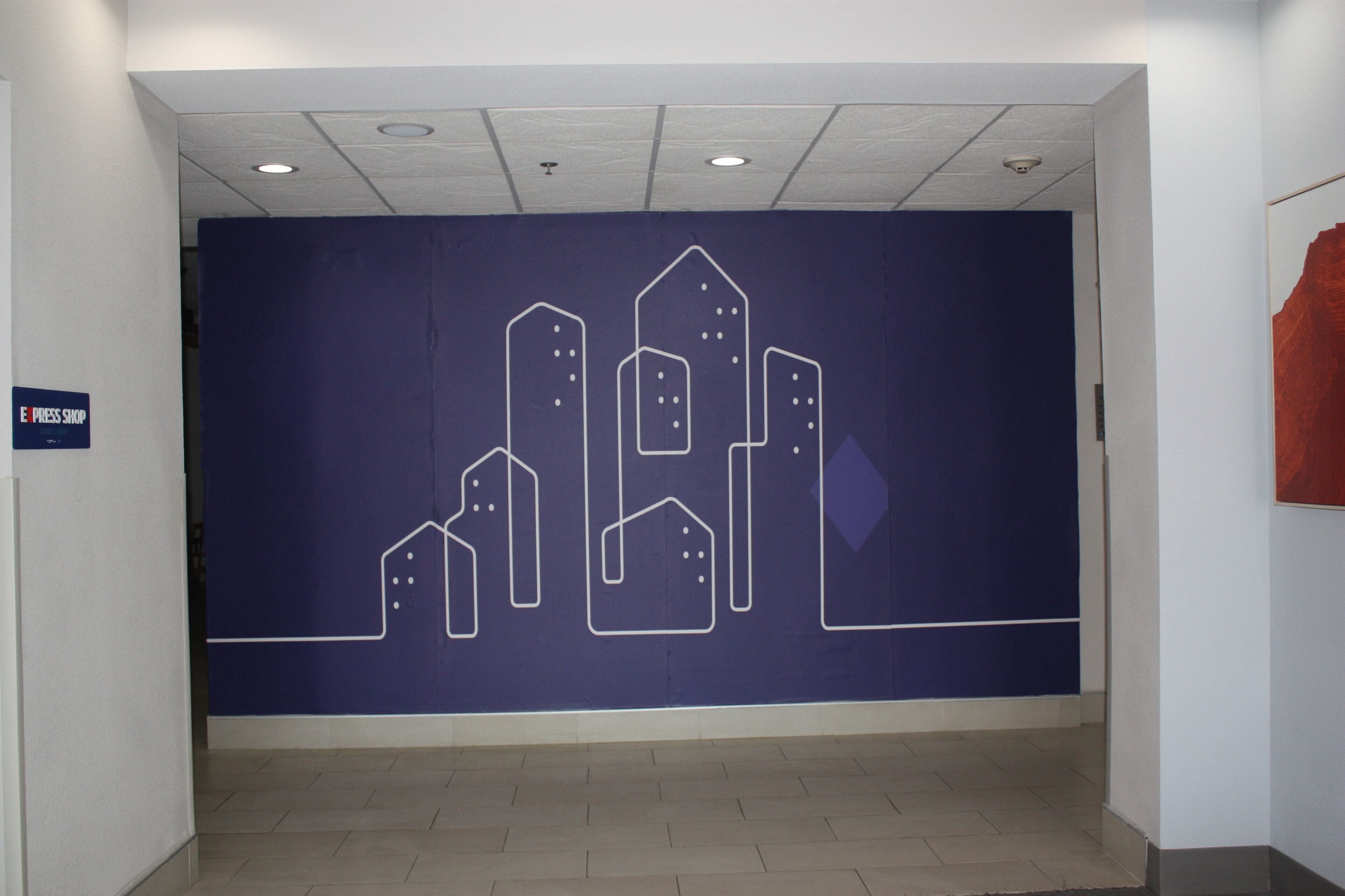 A hallway with a blue wall featuring a white line drawing of buildings.