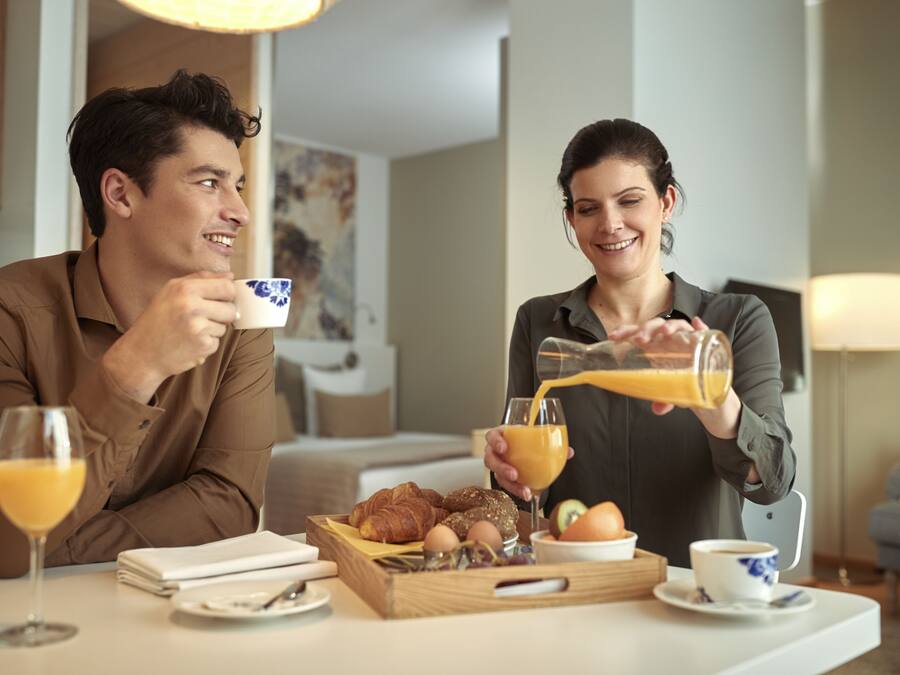 A breakfast setting with croissants, eggs, and orange juice on a tray.