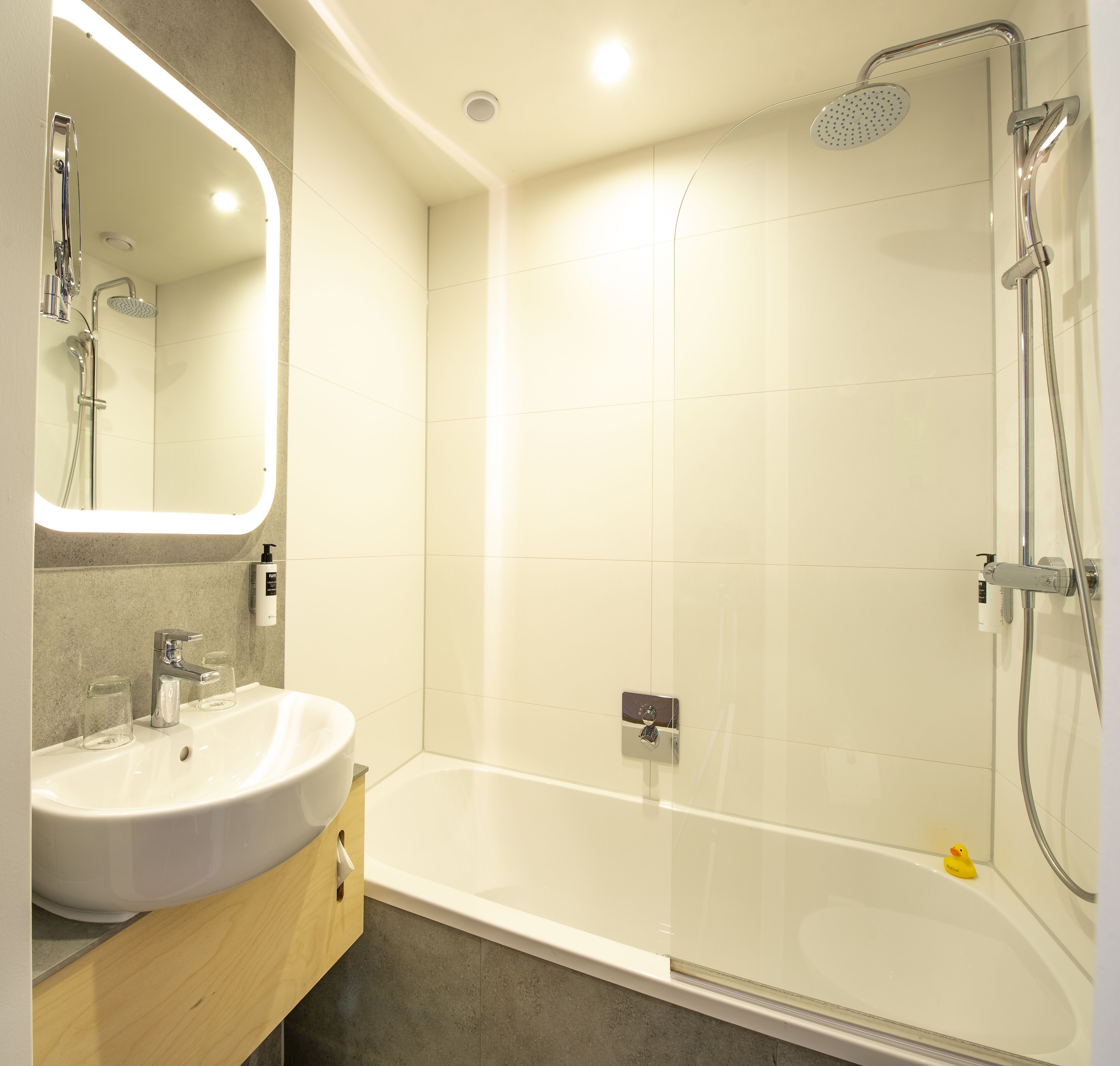 A modern bathroom with a bathtub, shower, and sink.