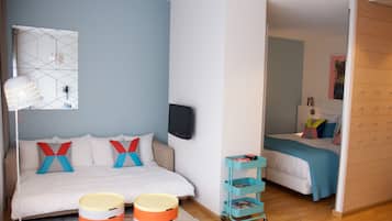 A modern bedroom with a bed, a TV, a desk, and a wardrobe.