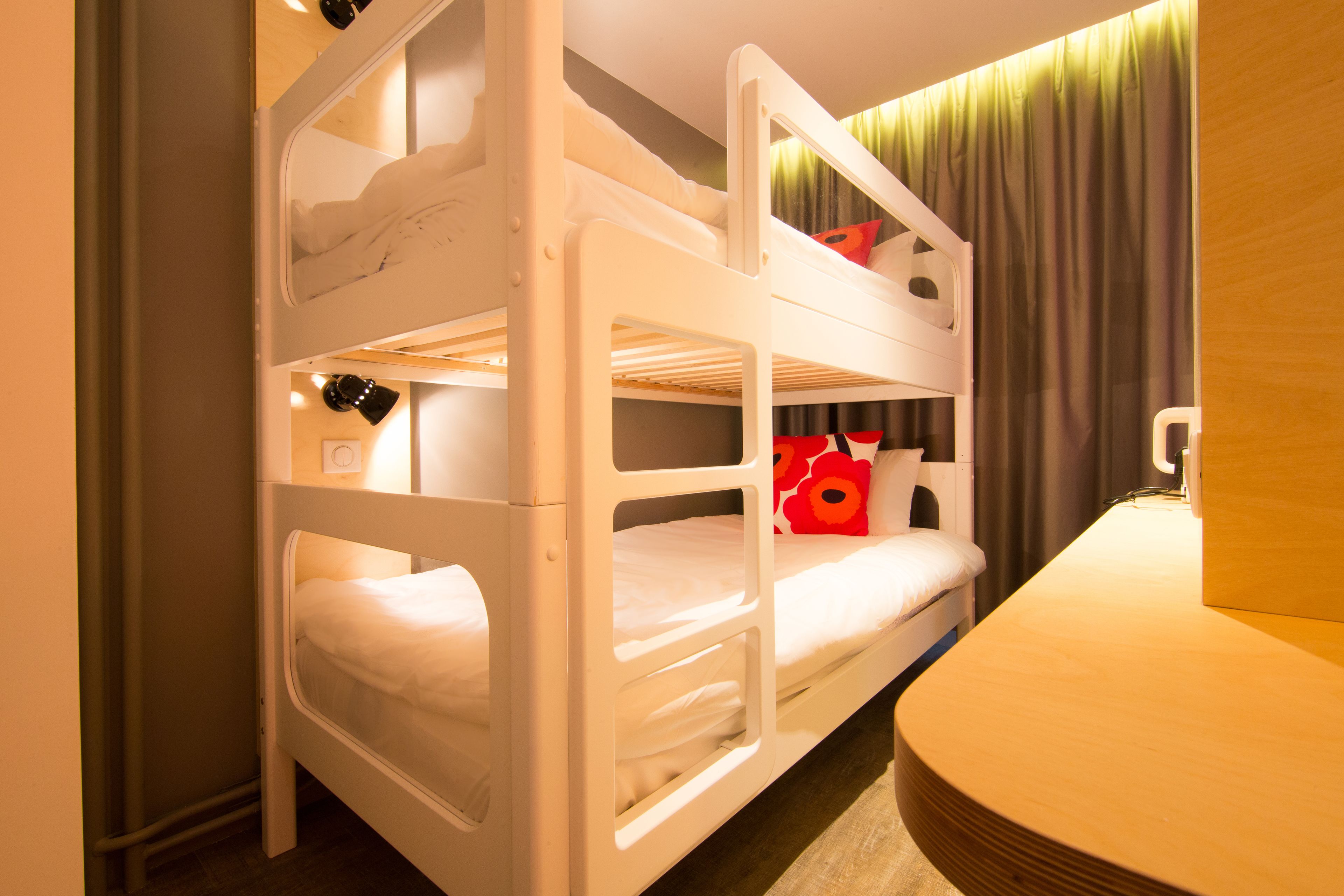 A bunk bed with white bedding and a red flower pillow.