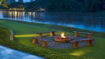 A lakeside outdoor seating area with a fire pit and benches.