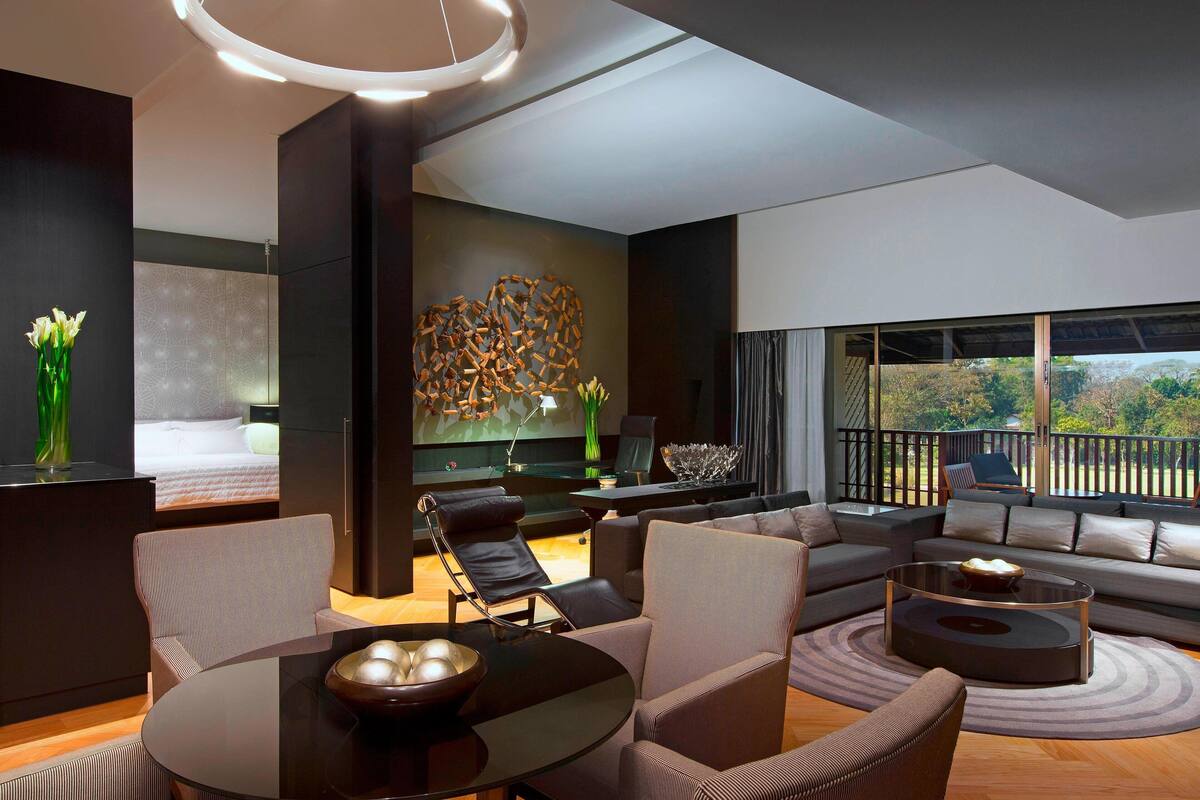 Un salon moderne avec un canapé, des fauteuils, une table basse et une grande fenêtre donnant sur un beau paysage.