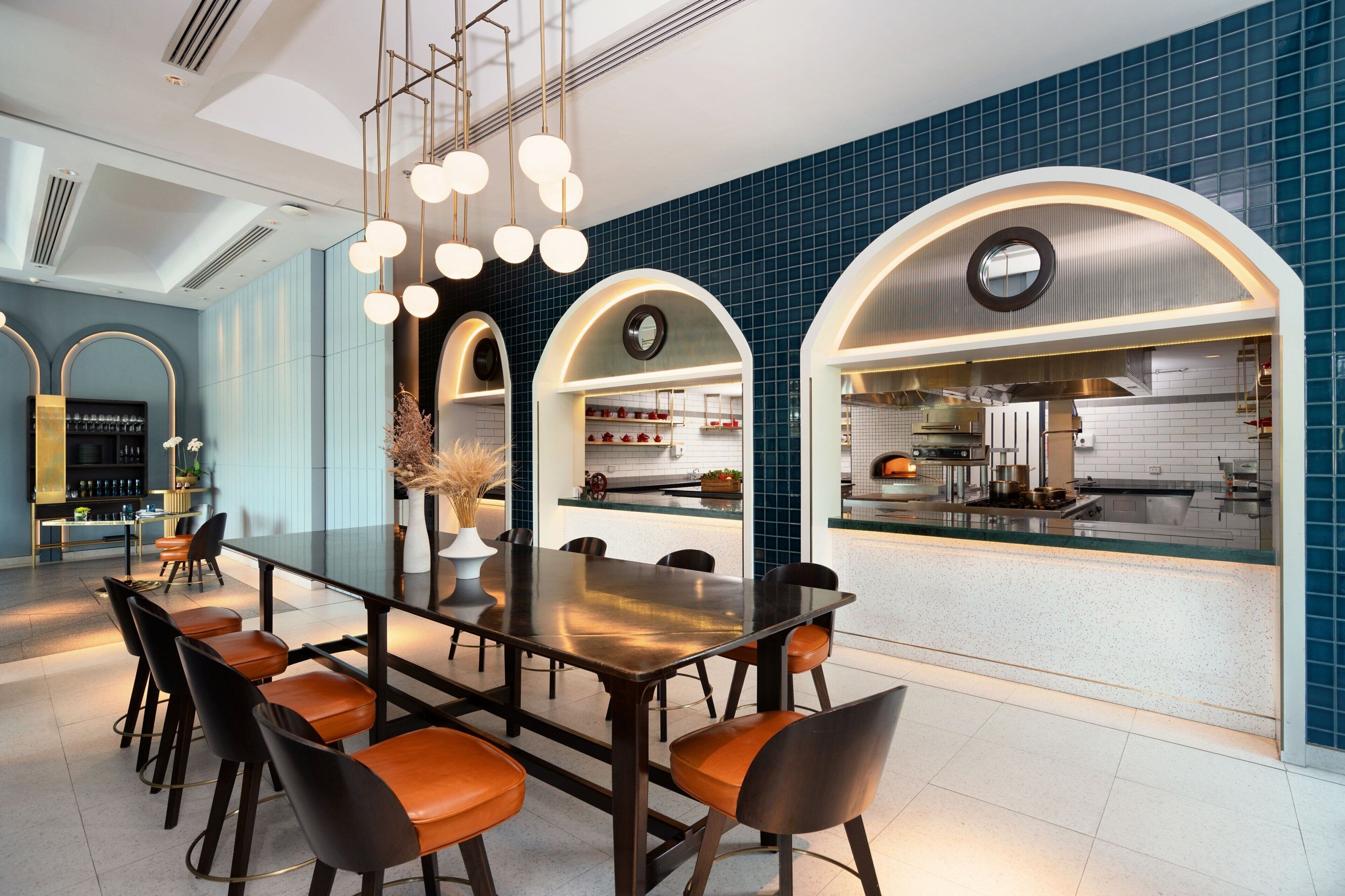 Cocina moderna con una isla central, un área de comedor con una mesa larga y sillas, y una barra con taburetes.