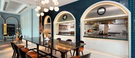 Cocina moderna con una isla central, un área de comedor con una mesa larga y sillas, y una barra con taburetes.