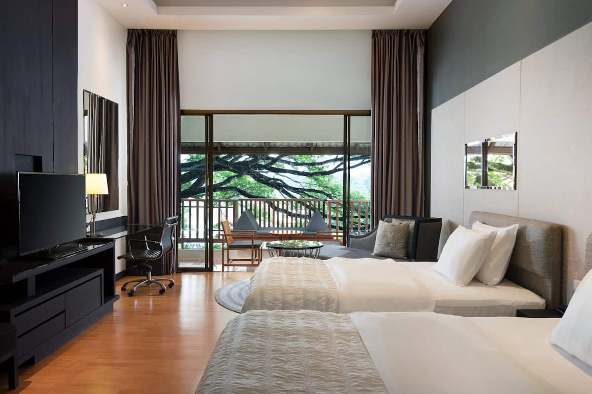 Une chambre d’hôtel moderne dotée d’une grande fenêtre, d’un téléviseur à écran plat, d’un bureau avec une chaise et de deux lits.