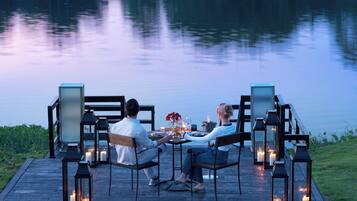 Una pareja cenando en una mesa con velas, con vistas a un cuerpo de agua.