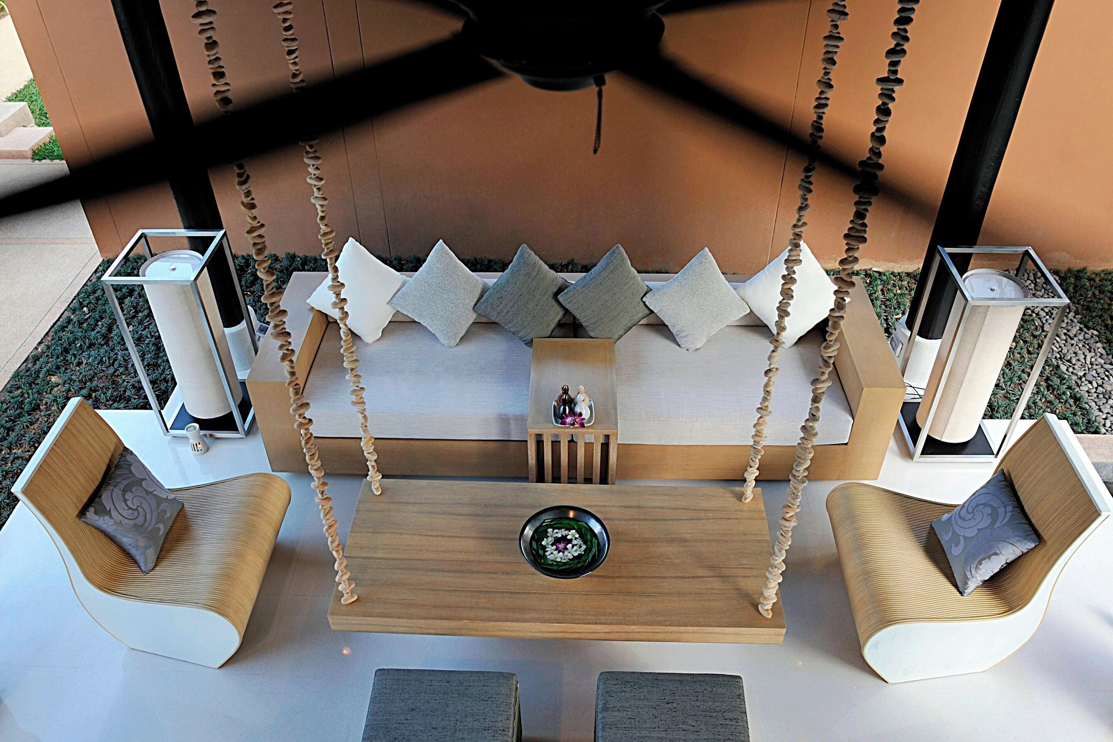 Un espace extérieur moderne, aménagé avec des sièges, dont une balançoire et des fauteuils rembourrés, ainsi qu’une table centrale.