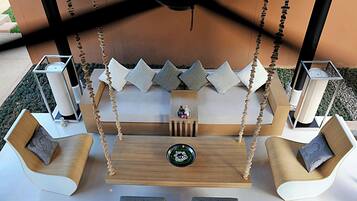 Un espace extérieur moderne, aménagé avec des sièges, dont une balançoire et des fauteuils rembourrés, ainsi qu’une table centrale.