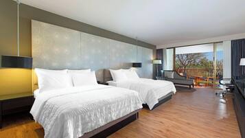 Quarto de hotel moderno com duas camas, varanda e vista para o exterior.
