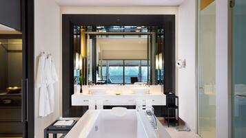 A modern bathroom with a large bathtub, dual sinks, and a large mirror.