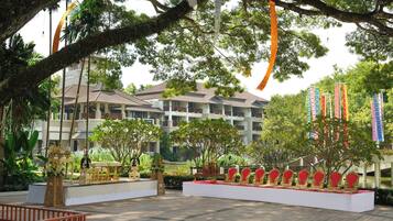 Un patio de hotel con un escenario, asientos y un árbol grande.