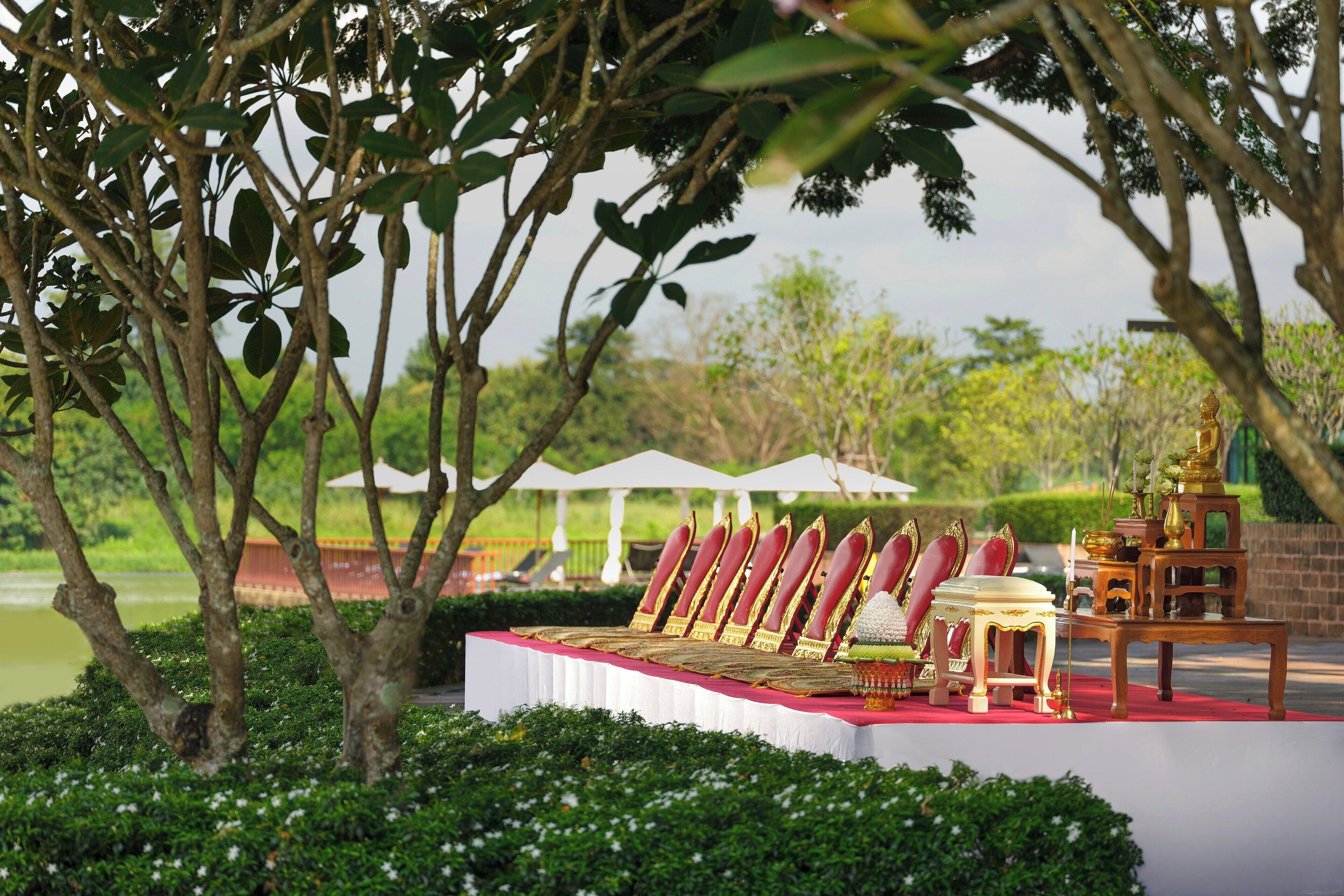 A banquet table set with red and gold chairs, a tiered stand, and a white tablecloth.