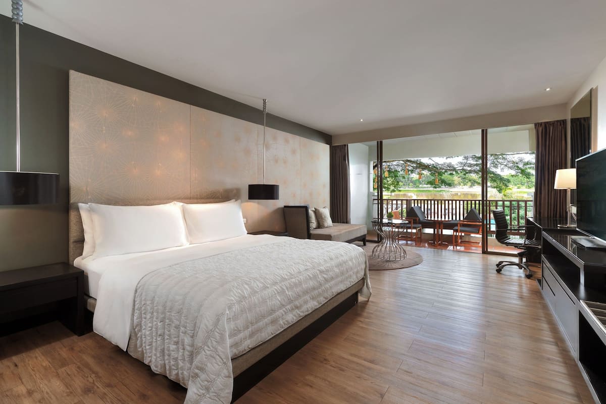 Une chambre d’hôtel moderne dotée d’un grand lit, d’une télévision et d’un balcon avec coin salon extérieur.