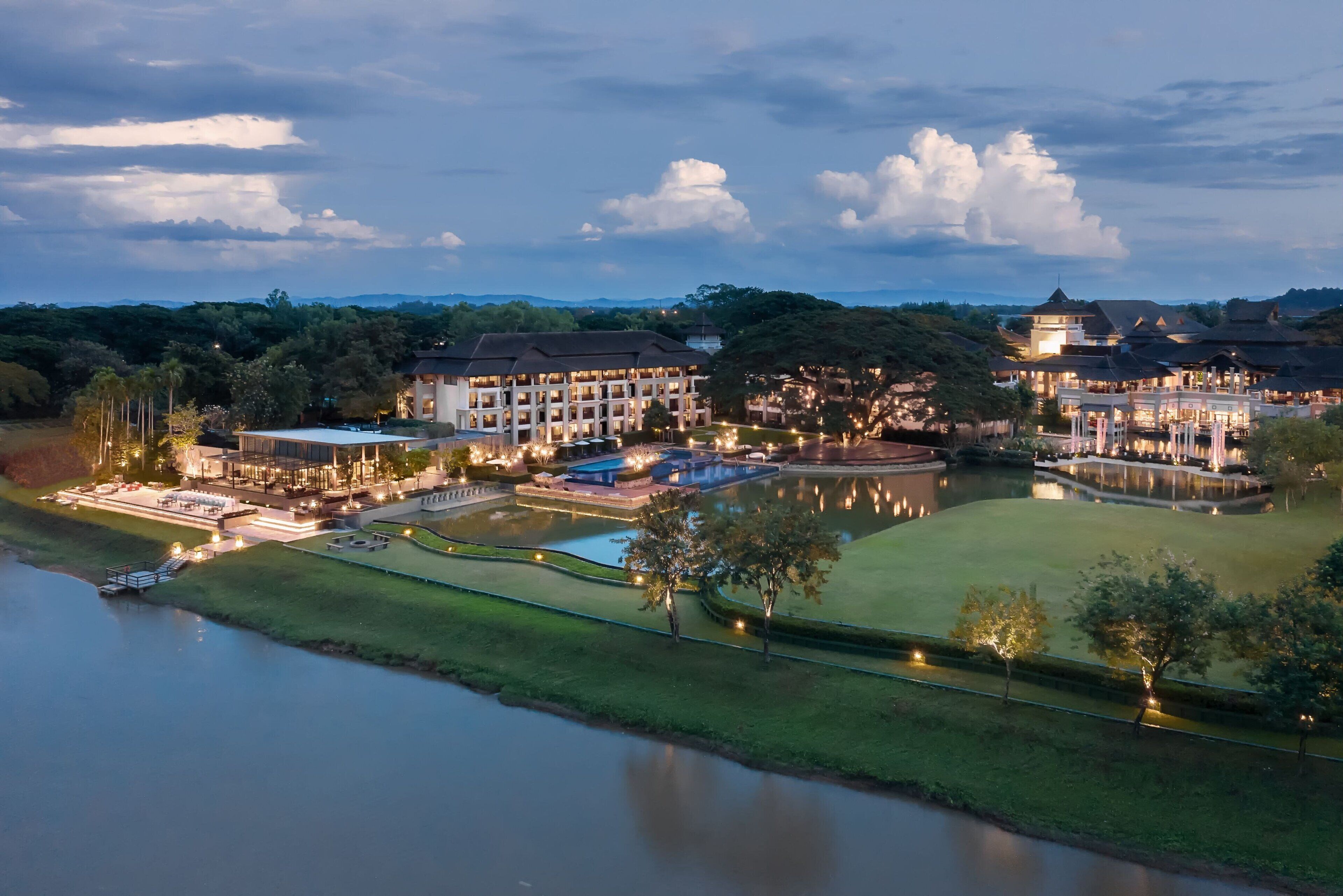 A large hotel with multiple buildings, a swimming pool, and a lake.