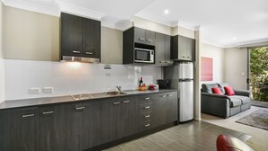 Una cocina moderna con armarios oscuros, un refrigerador de acero inoxidable y un microondas.