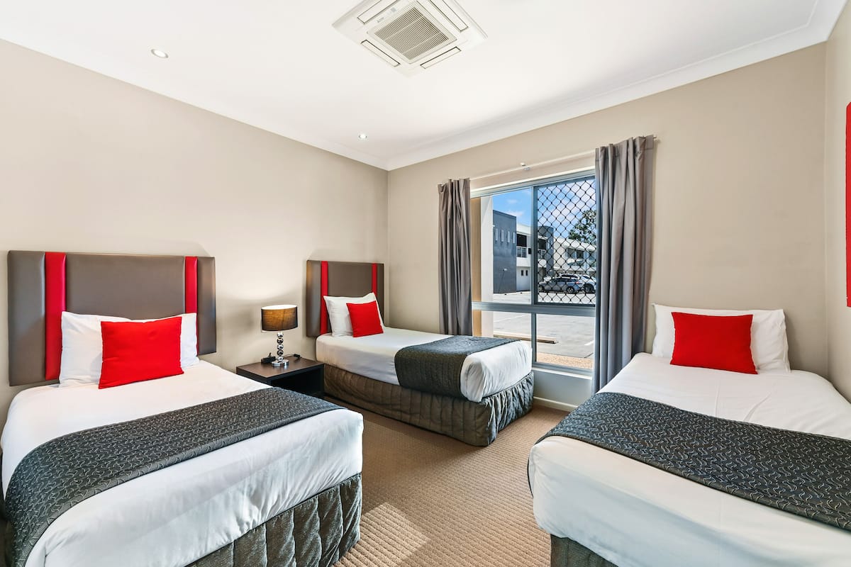 Habitación de hotel con dos camas, un ventanal grande y vistas al exterior.