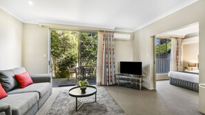 Una sala de estar moderna con un sofá gris, una mesa de centro con una planta, un televisor de pantalla plana y un balcón con puerta corrediza.