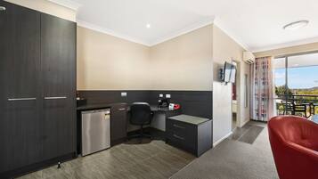 A modern kitchen with dark cabinetry, a small refrigerator, and a black office chair.