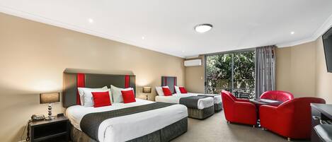 A hotel room with two beds, a desk, a chair, and a TV.