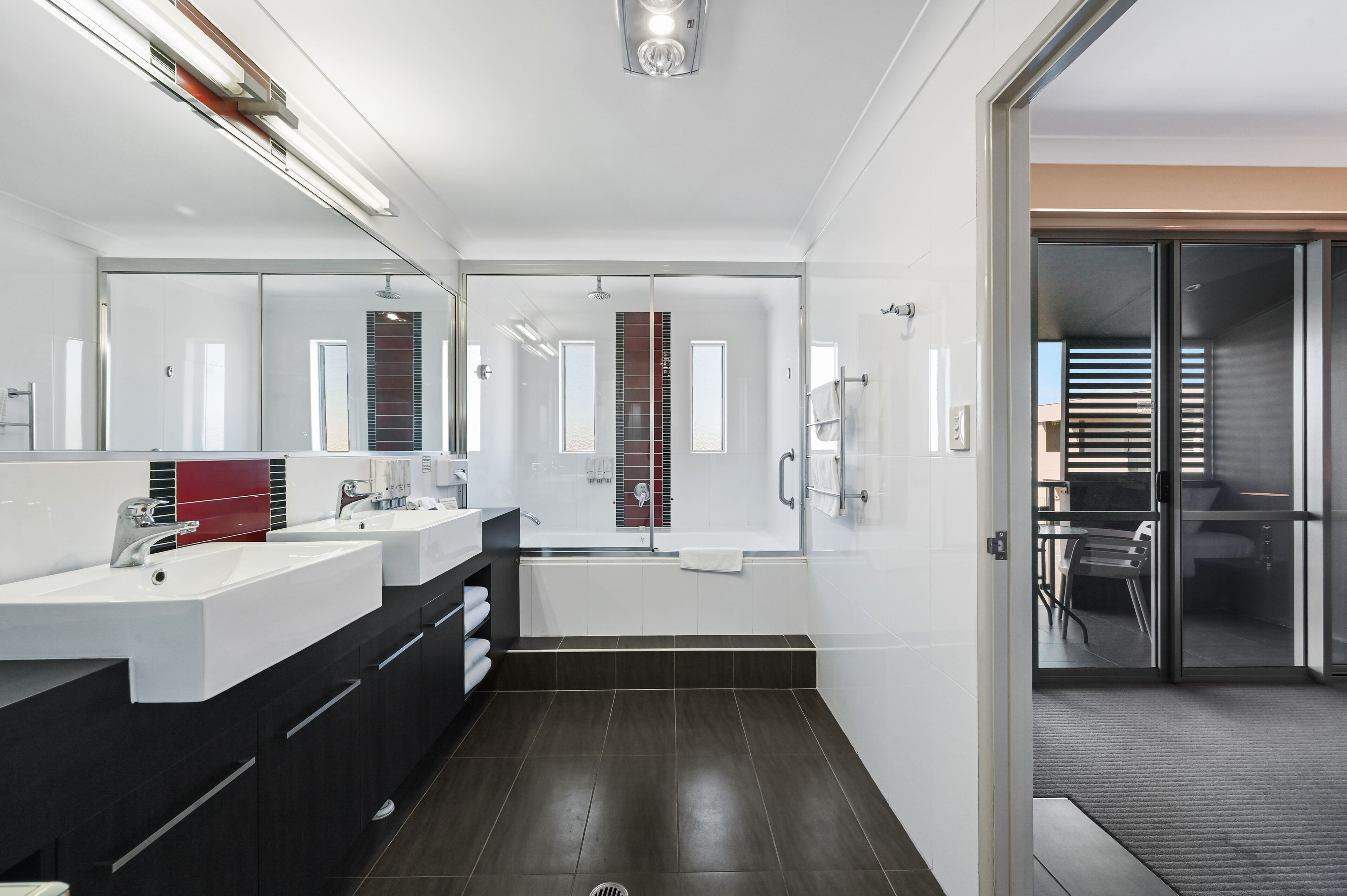 A modern bathroom with a glass shower enclosure, a large mirror, and a dual sink vanity.