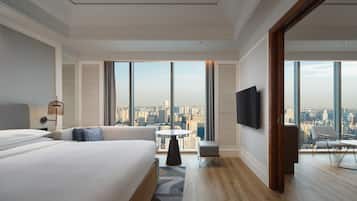A modern hotel room with a large bed, a small round table, a sofa, and a TV.