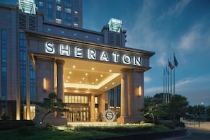 A Sheraton hotel entrance with a grand facade, large columns, and a well-lit entrance. - Sheraton Shanghai Pudong Riverside (Shanghai)