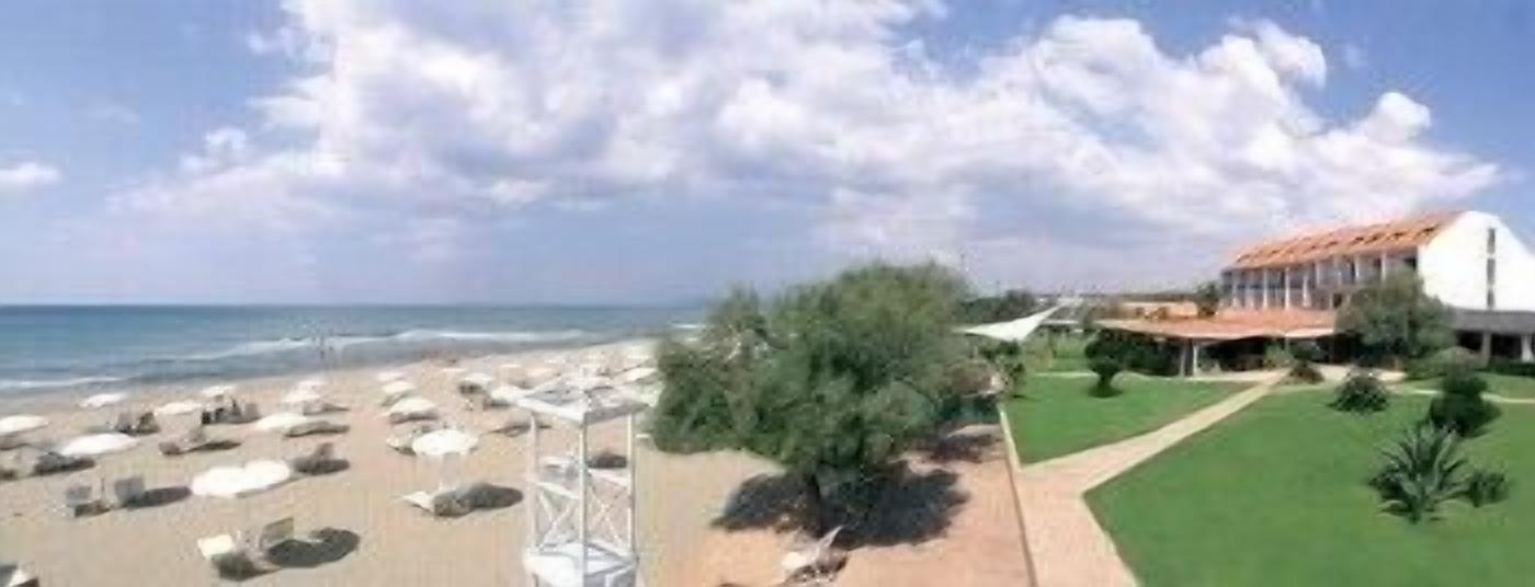 A beach with sun loungers and a building with a red roof.