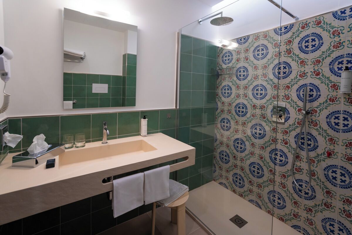 Un baño con lavamanos, espejo y ducha.