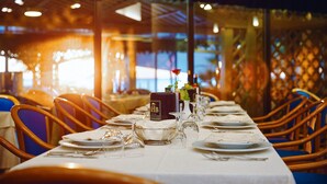 Une table de restaurant dressée avec des assiettes, des verres et un présentoir à menus.