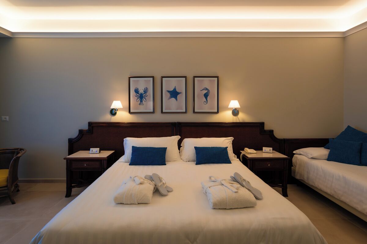 A hotel room with a large bed, two bedside tables, a chair, and three wall-mounted lamps.