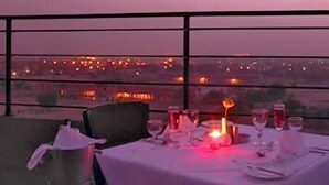 A table set for dining with a city view in the background. - Hotel Paradise (Jaipur)