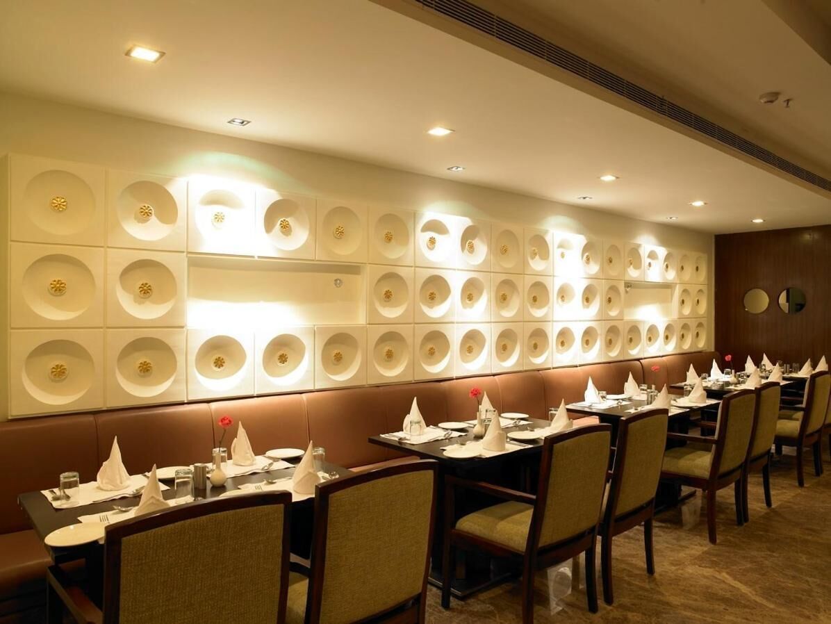 A restaurant with a long counter, multiple tables, and a decorative wall with circular patterns.