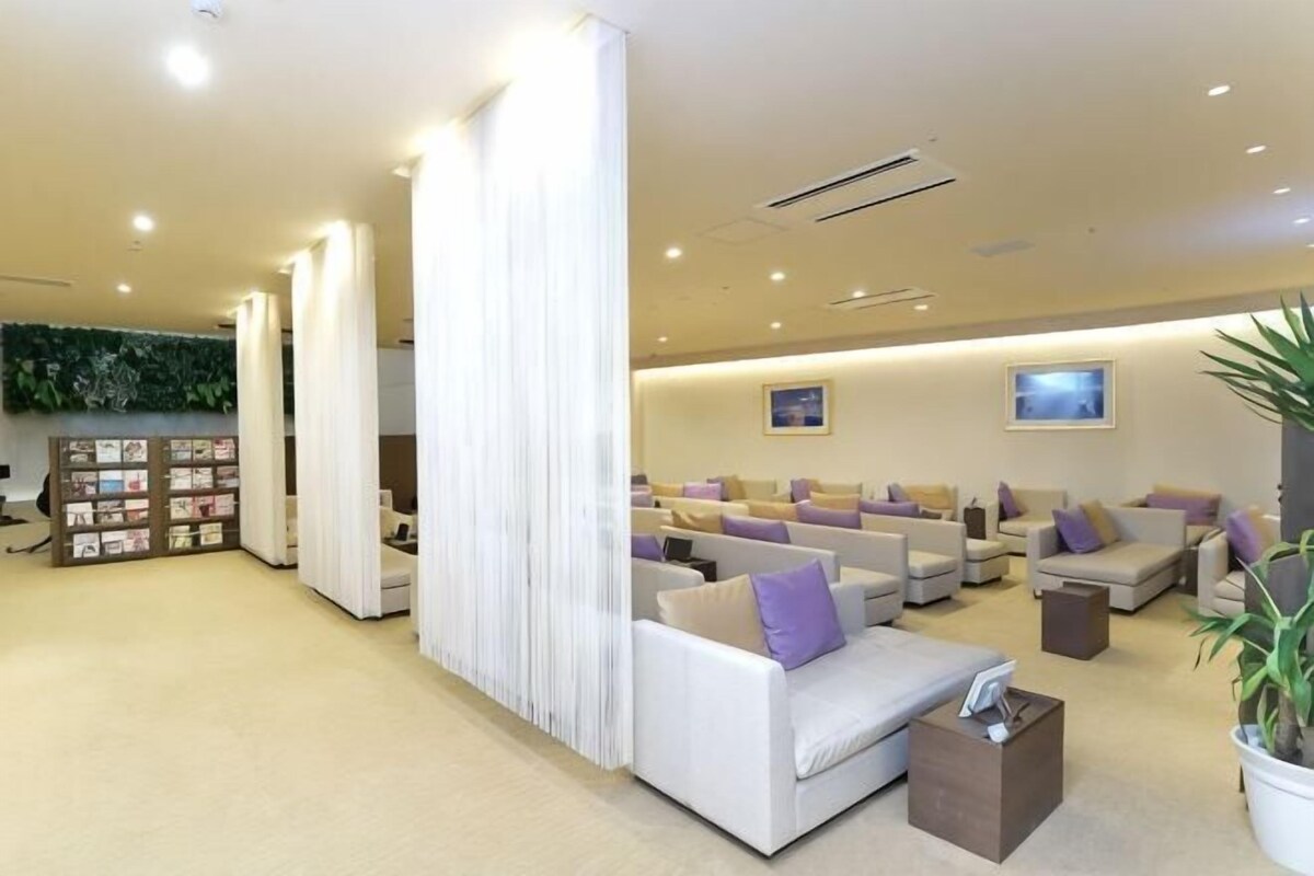 A modern hotel lobby with seating areas, a reception desk, and a bookshelf.