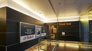 A modern hotel lobby with a reception desk, a glass partition, and informational posters on the wall. - Sotetsu Fresa Inn Higashi Shinjuku (Tokyo)