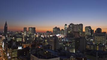 A city skyline at dusk with illuminated buildings and a prominent hotel labeled "CHOTEL" in the foreground.