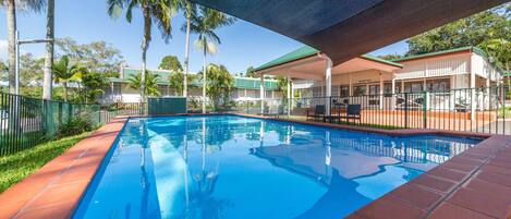 Una piscina al aire libre, sillones reclinables de piscina