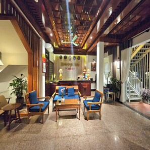 A lobby with a reception desk, wooden furniture, a staircase, and a ceiling with exposed beams. - Victory Hotel Hue (Hue)