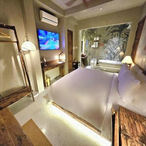 A bedroom with a large bed, a television mounted on the wall, a wooden dresser, and a mirror. - Victory Hotel Hue (Hue)