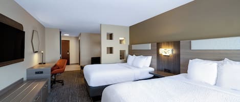 Una habitación de hotel con dos camas, un escritorio, una silla y un televisor.