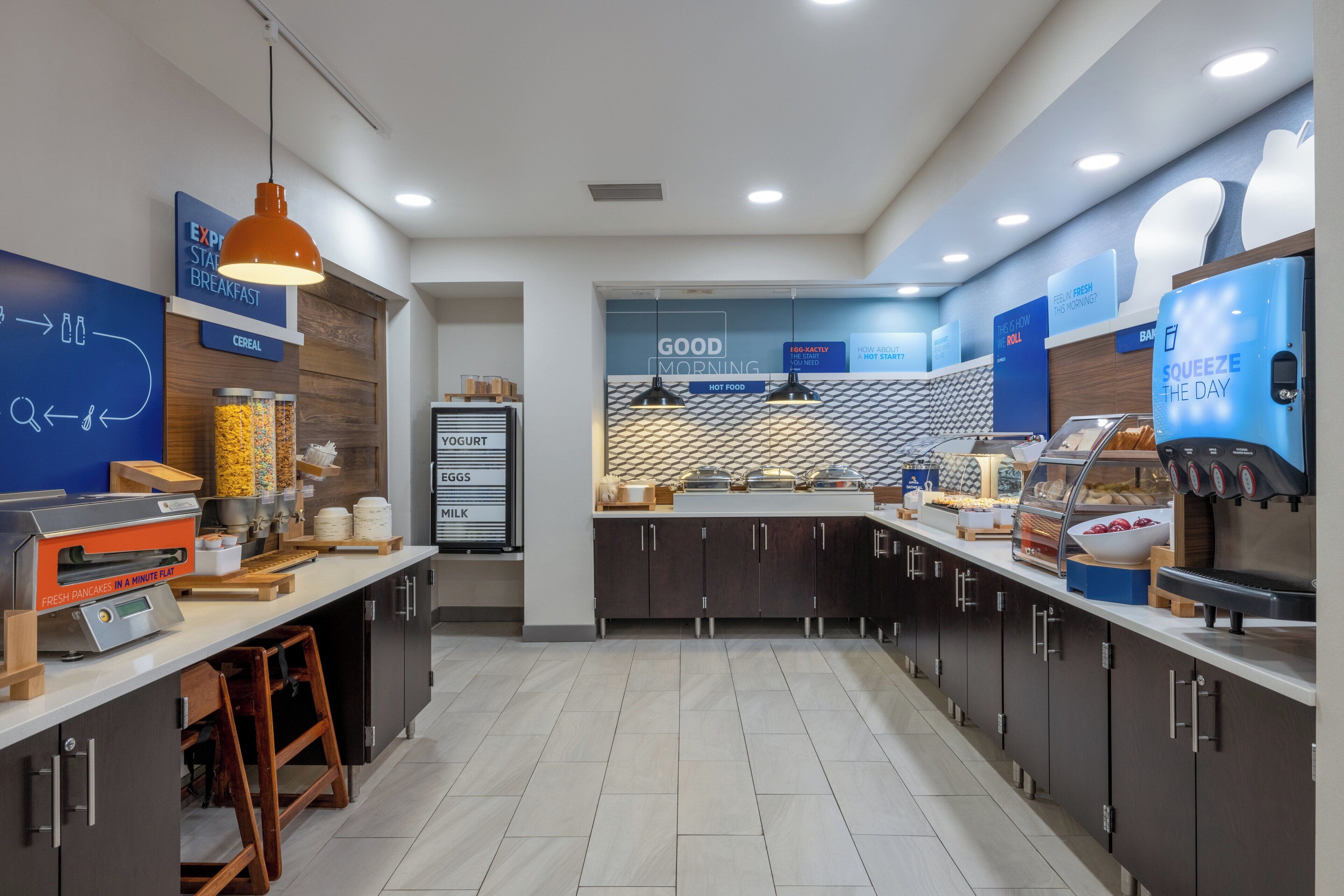 A modern breakfast area with a self-serve station, a yogurt display, and a sign reading "GOOD MORNING".