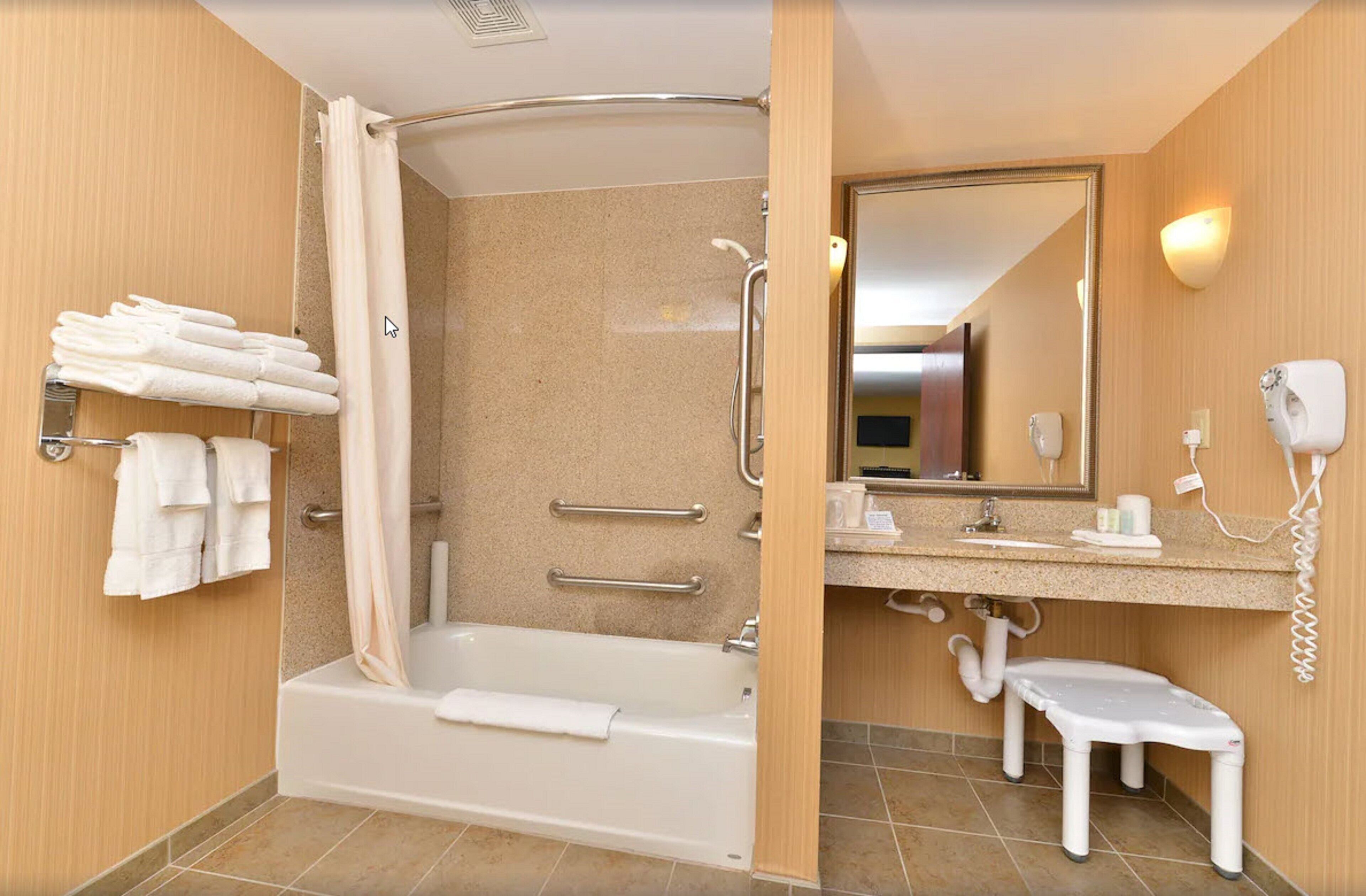 A modern bathroom with a walk-in shower, a bathtub, a toilet, a sink with a mirror, and a towel rack.