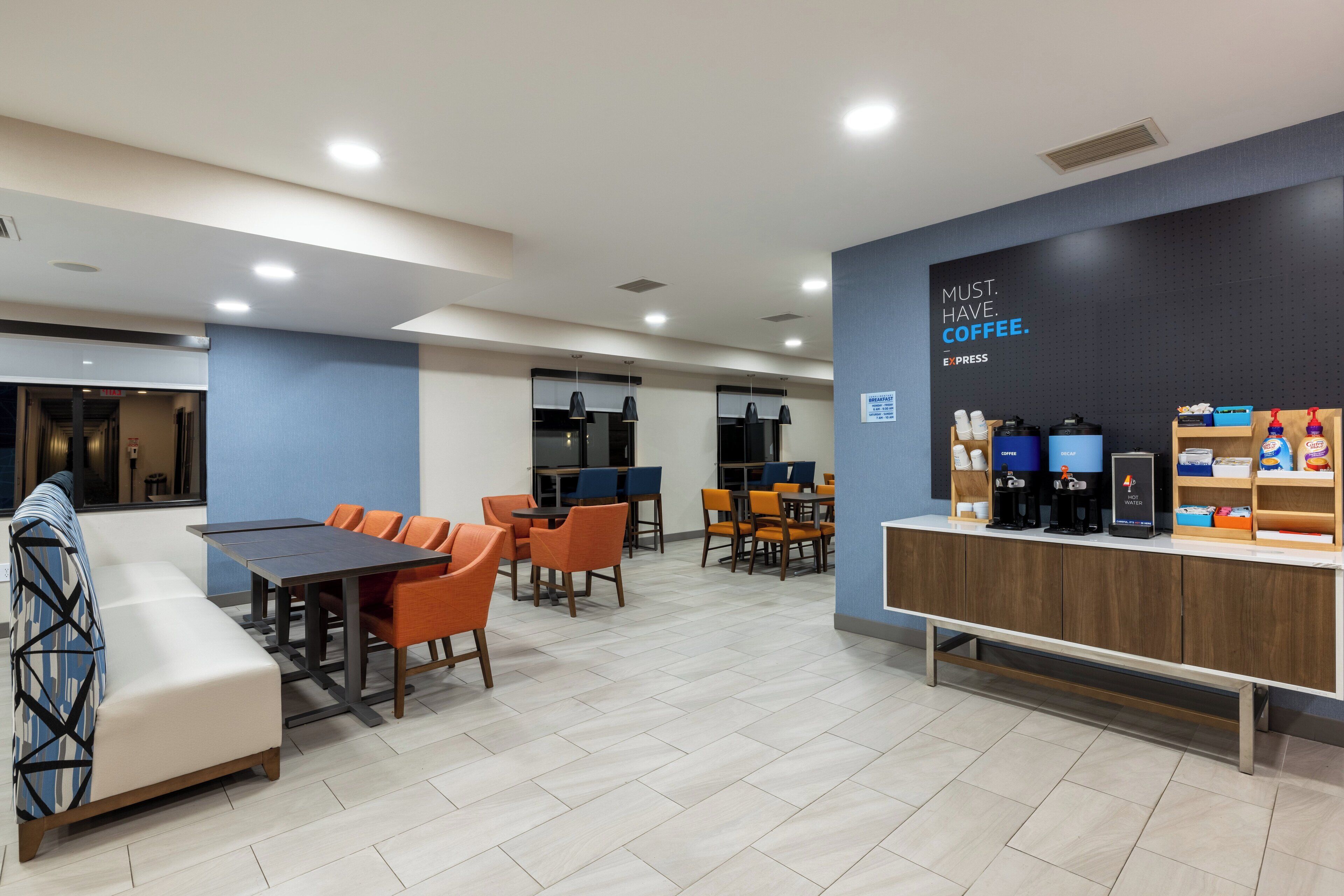 A modern hotel lobby with a seating area, a coffee station, and a reception desk.